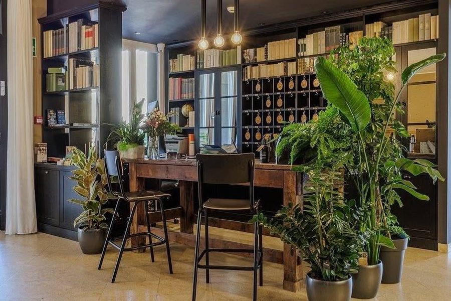 Reception con libreria a muro, tavolo in legno e sgabelli, a lavoro finito